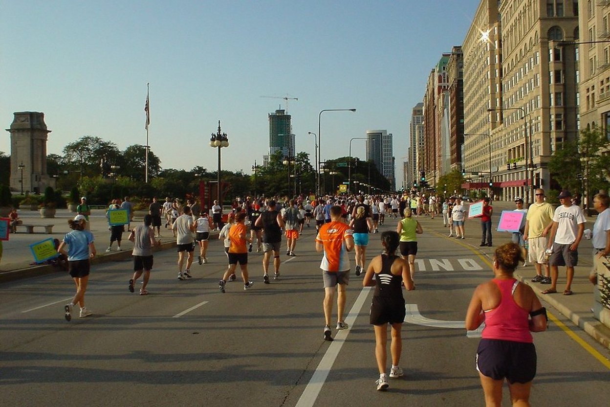 Runners on a closed downtown Chicago street during the Chicago Marathon, with spectators lining the curbs.
