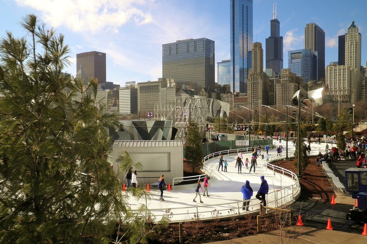 People ice skating at a rink with Chicago skyline in background.