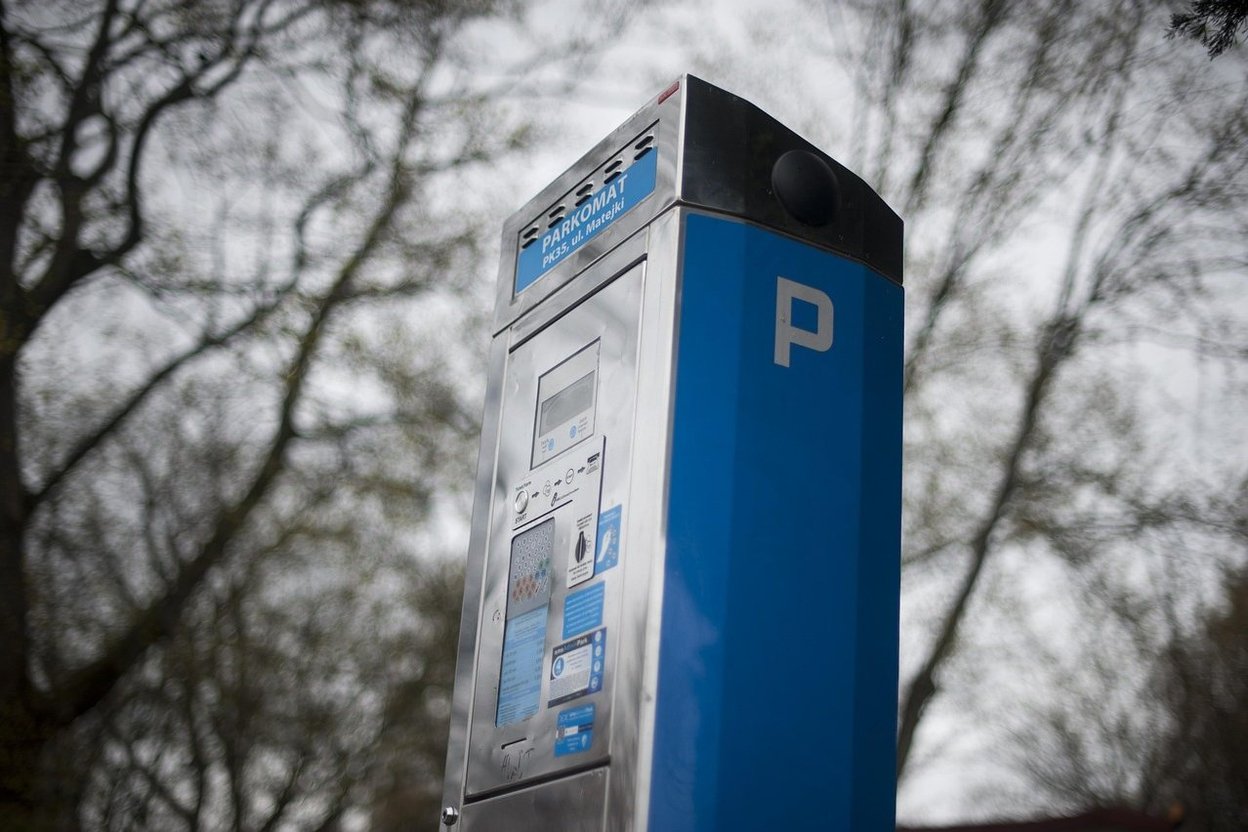 A row of Chicago parking meters along a city street, with a car parked at one of them.