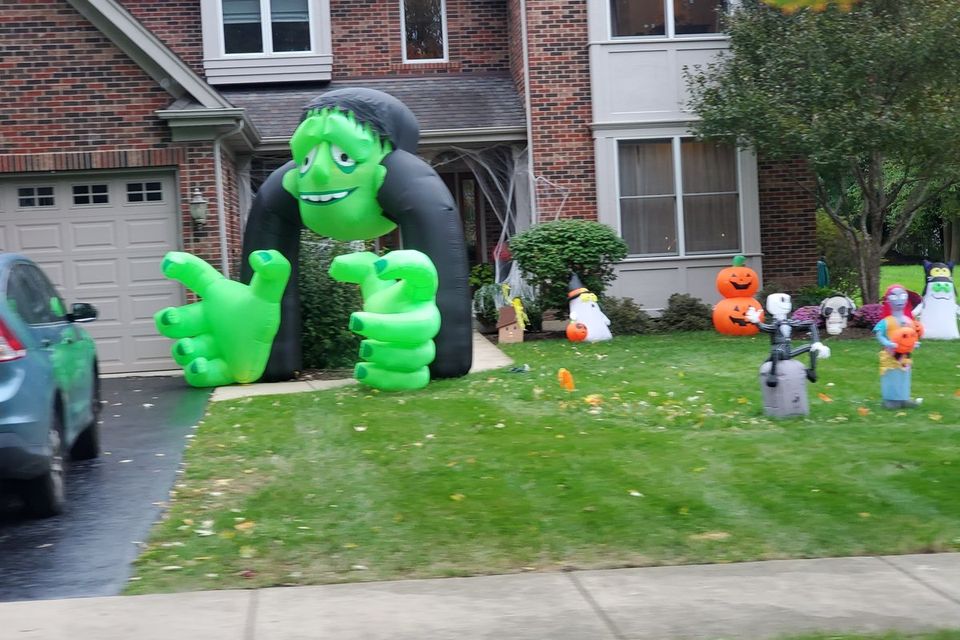 Inflatable monster hands reaching out of a green archway in a suburban Chicagoland front yard
